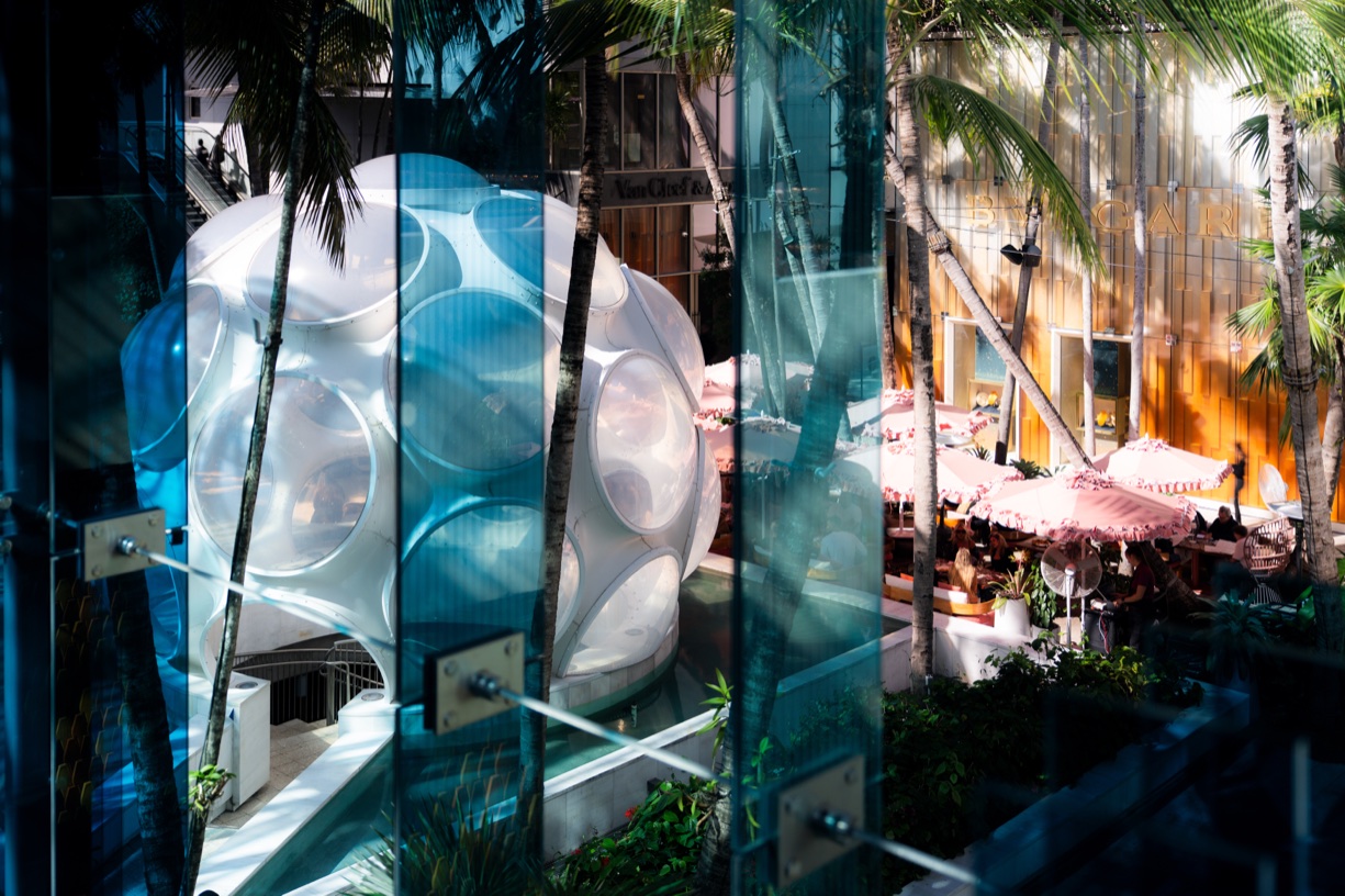 Spiegelglasfassade im Miami Design District reflektiert Palmen und eine geodätische Kuppelstruktur